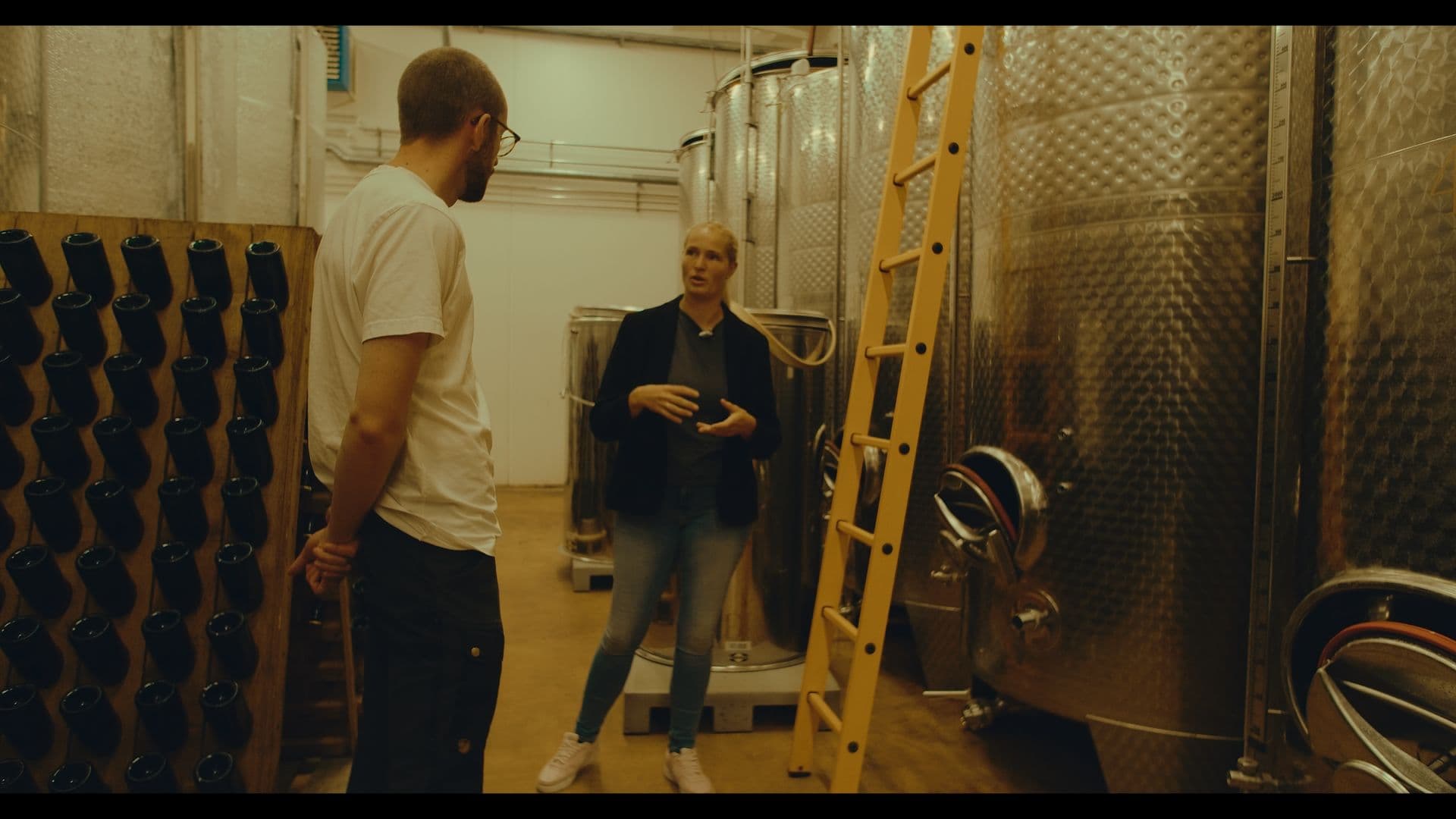 Mads Andersen og en medarbejder mellem ståltanke og flaskestativer i vineriet